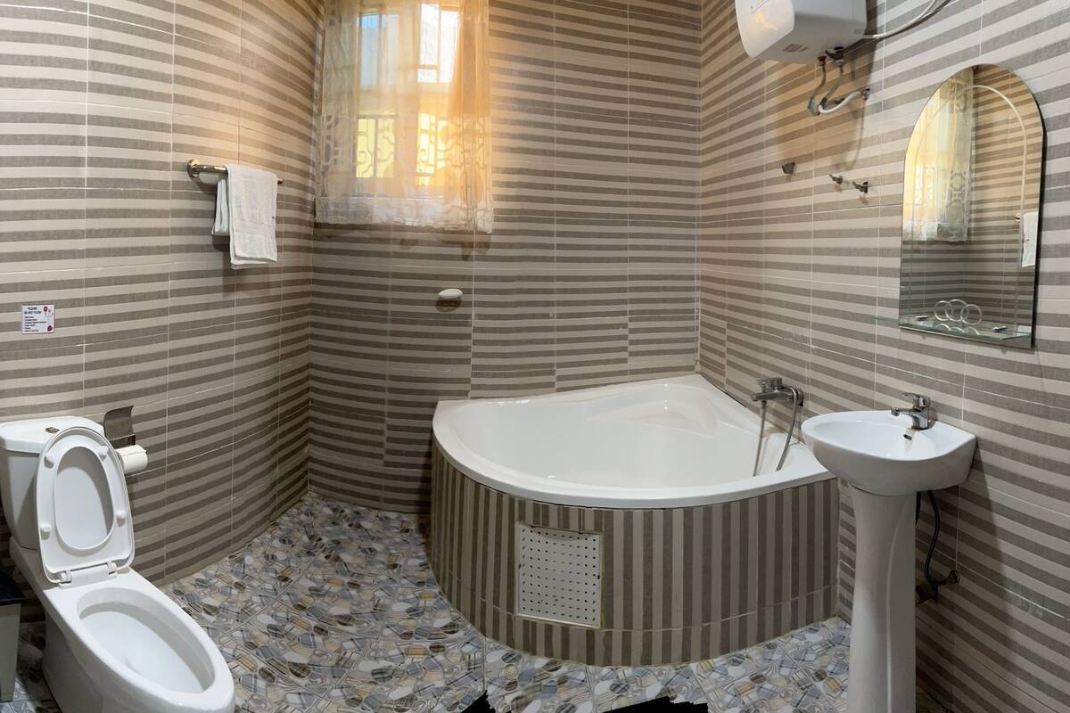 A bathroom with striped walls, a toilet, a bathtub, and a sink.