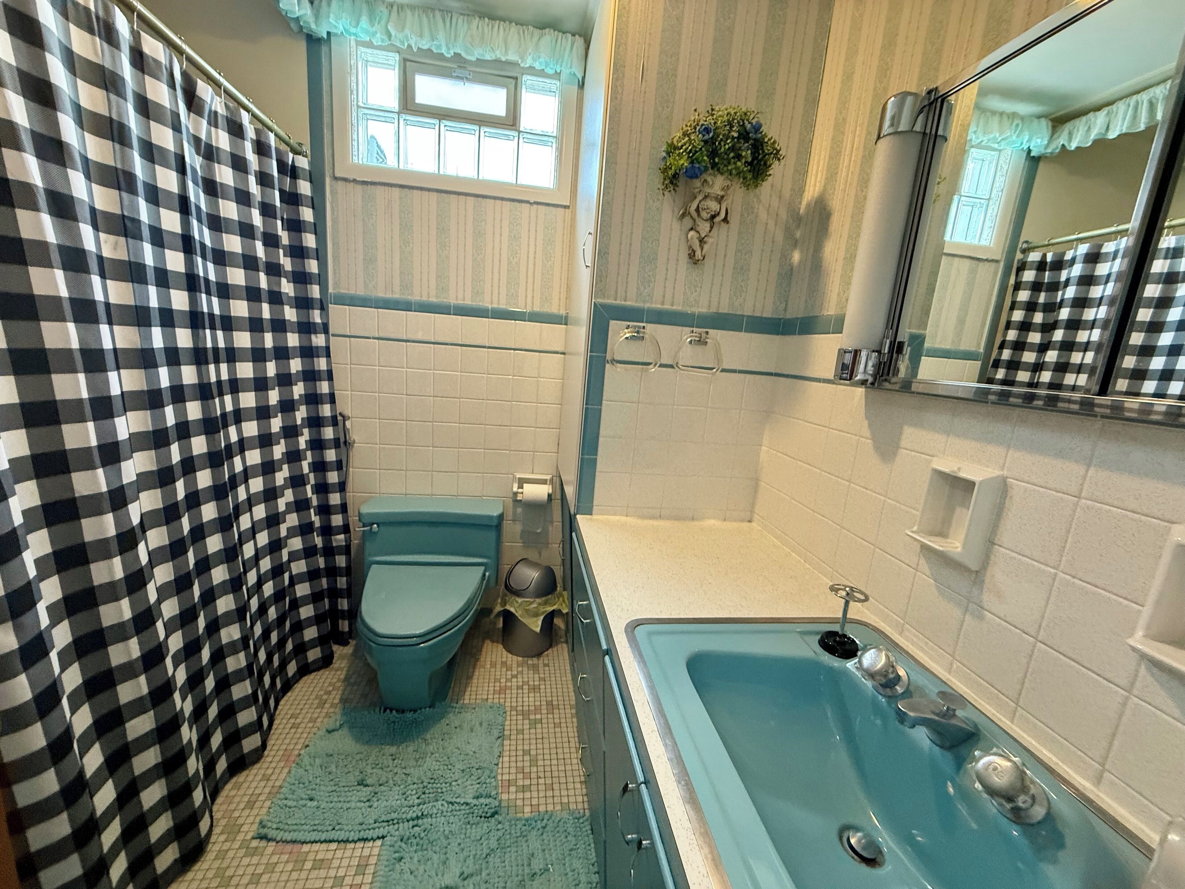 A bathroom with a checkered shower curtain, a toilet, a sink, and a bathtub.