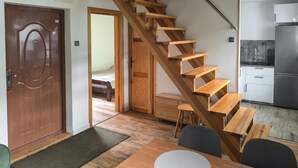 A compact kitchen with a built-in refrigerator, wooden staircase, and a dining area with a table and chairs. - Gorgeous home in Morag with lake view (Morag)