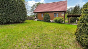 A two-story wooden house with a red-tiled roof, surrounded by well-maintained lawns and hedges. - Gorgeous home in Morag with lake view (Morag)