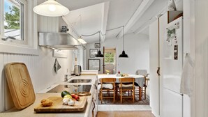 Een keuken met een houten snijplank, een spoelbak en een eethoek met stoelen en een tafel.