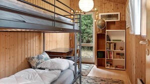 Een slaapkamer met stapelbedden, een houten inrichting, een wereldbol en een boekenplank.