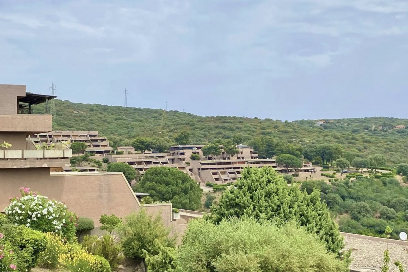 Zona residencial con varios edificios de apartamentos, rodeada de vegetación y colinas.