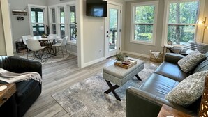A spacious living room with a fireplace, a dining area, and a TV mounted on the wall. - Large Home in Tiny Home Lake Community-Retreat at Water's Edge (Tracy City)