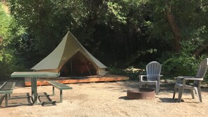 A tent with a fire pit and two Adirondack chairs in a forested area. - Sequoia Jewel -16 Foot Bell Tent with double beds. 4.5 to Sequoia National Park. (Three Rivers)