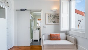 Una sala moderna con un sofá, un cojín con la palabra "grateful", una obra de arte enmarcada y un letrero para los baños.