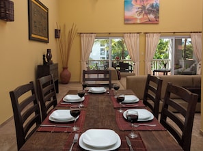 A dining area with a table set for four, a vase of dried reeds, and a painting of a sunset. - Ocean Dream Cabarete (Cabarete)