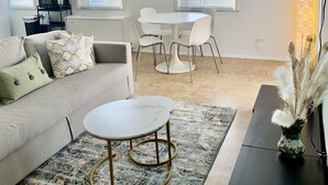 A modern living room with a sofa, a round coffee table, and a dining area with chairs. - ATL Downtown Condo w Balcony with City views (Atlanta)