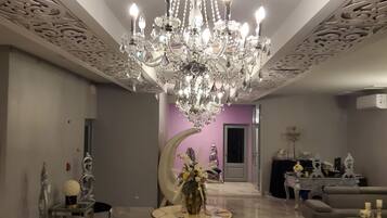 A spacious lobby with a large chandelier, marble flooring, and a unique ceiling design.