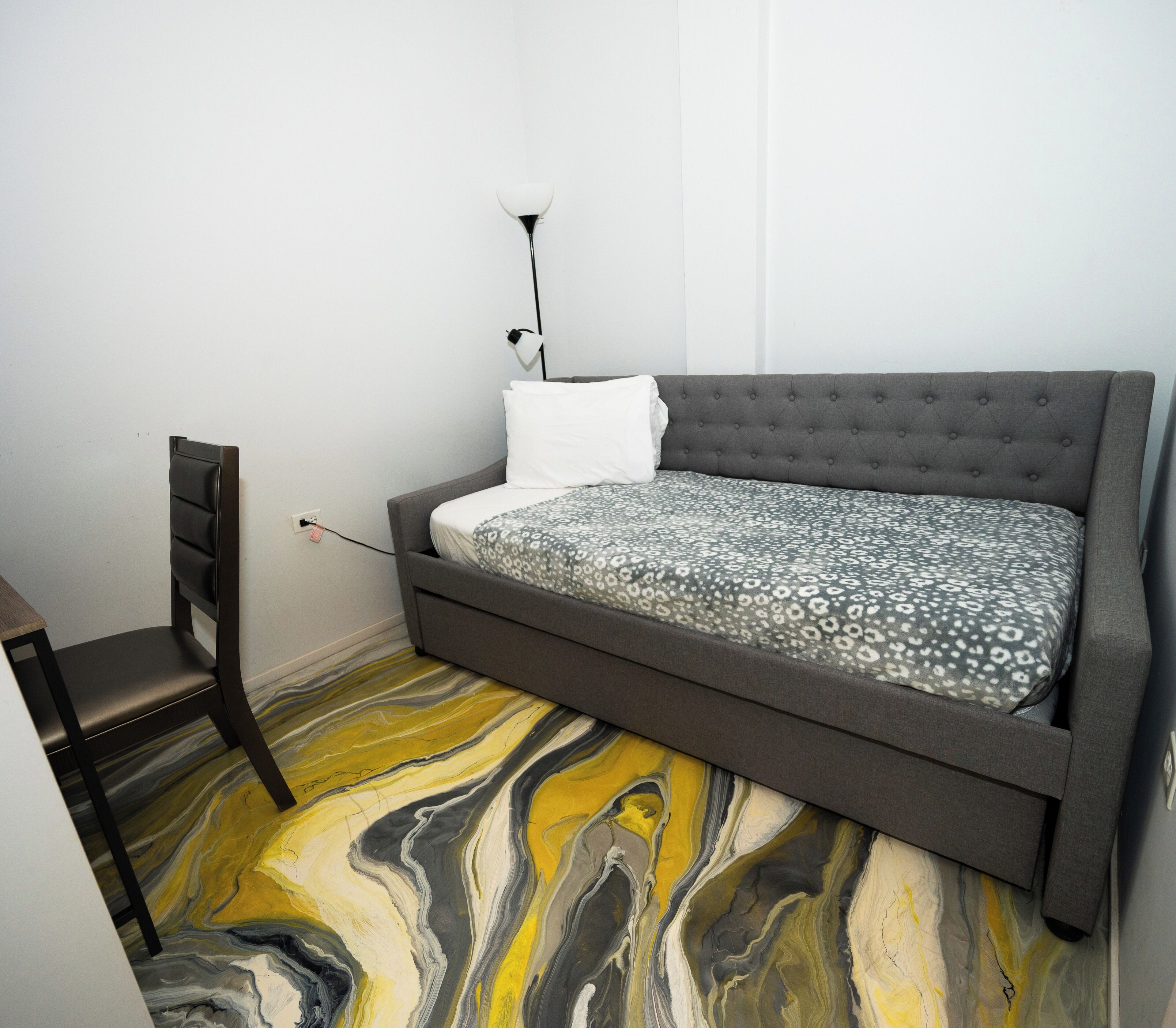 Ein Schlafzimmer mit einem Bett, einem Sessel und einem Boden mit Marmoroptik.