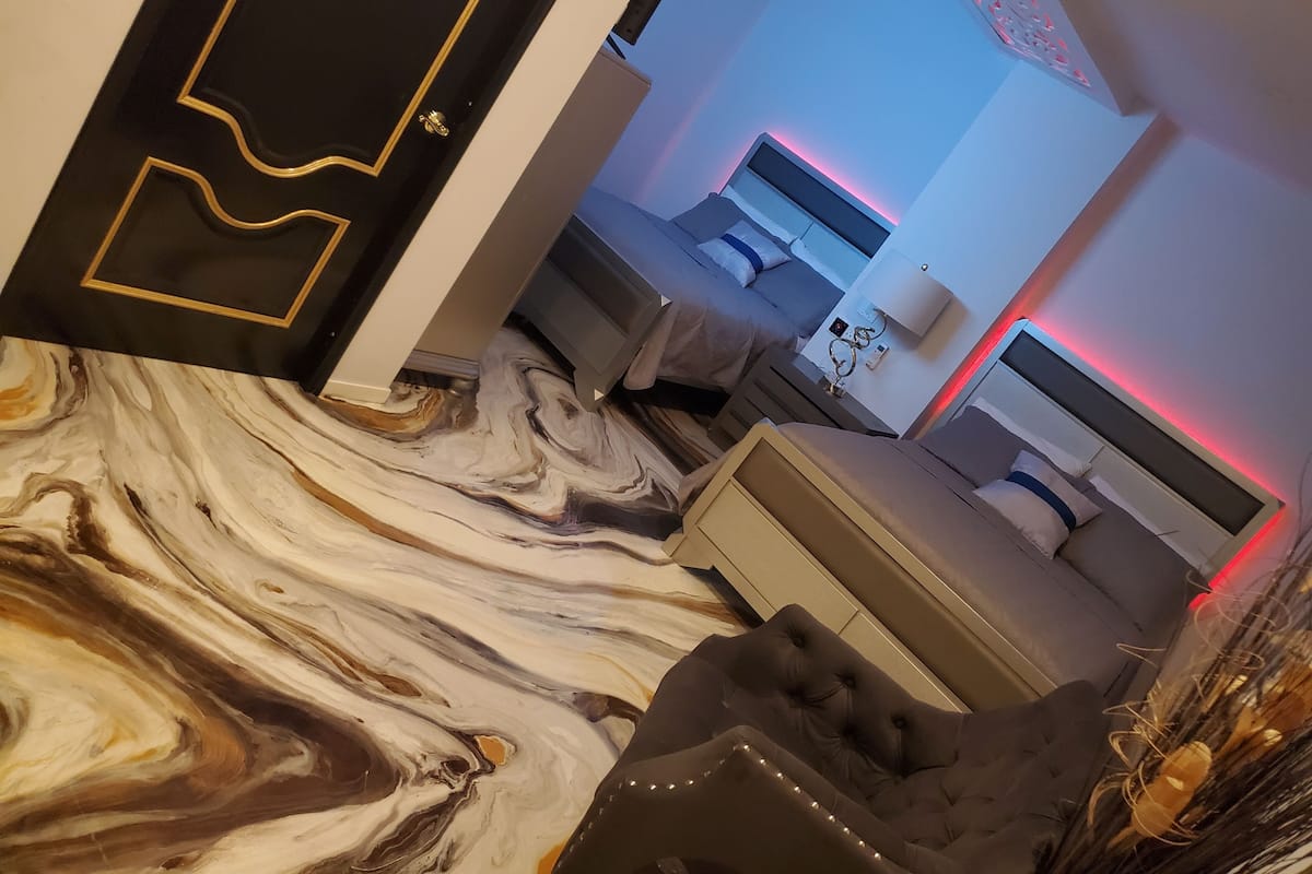 A modern hotel room with a marble floor, a sofa, a bed, and a nightstand.