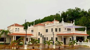 A large, multi-story building with a symmetrical facade, multiple balconies, and a central courtyard with palm trees. - Luxury Puerto Caribe Boutique Hotel (Aguada)
