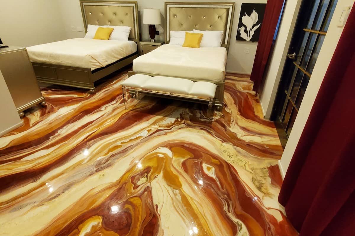 A hotel room with two beds, a marble-patterned floor, and a red curtain.