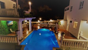 A swimming pool with a pergola and seating area, surrounded by a white building with columns and a small garden. - Luxury Puerto Caribe Boutique Hotel (Aguada)
