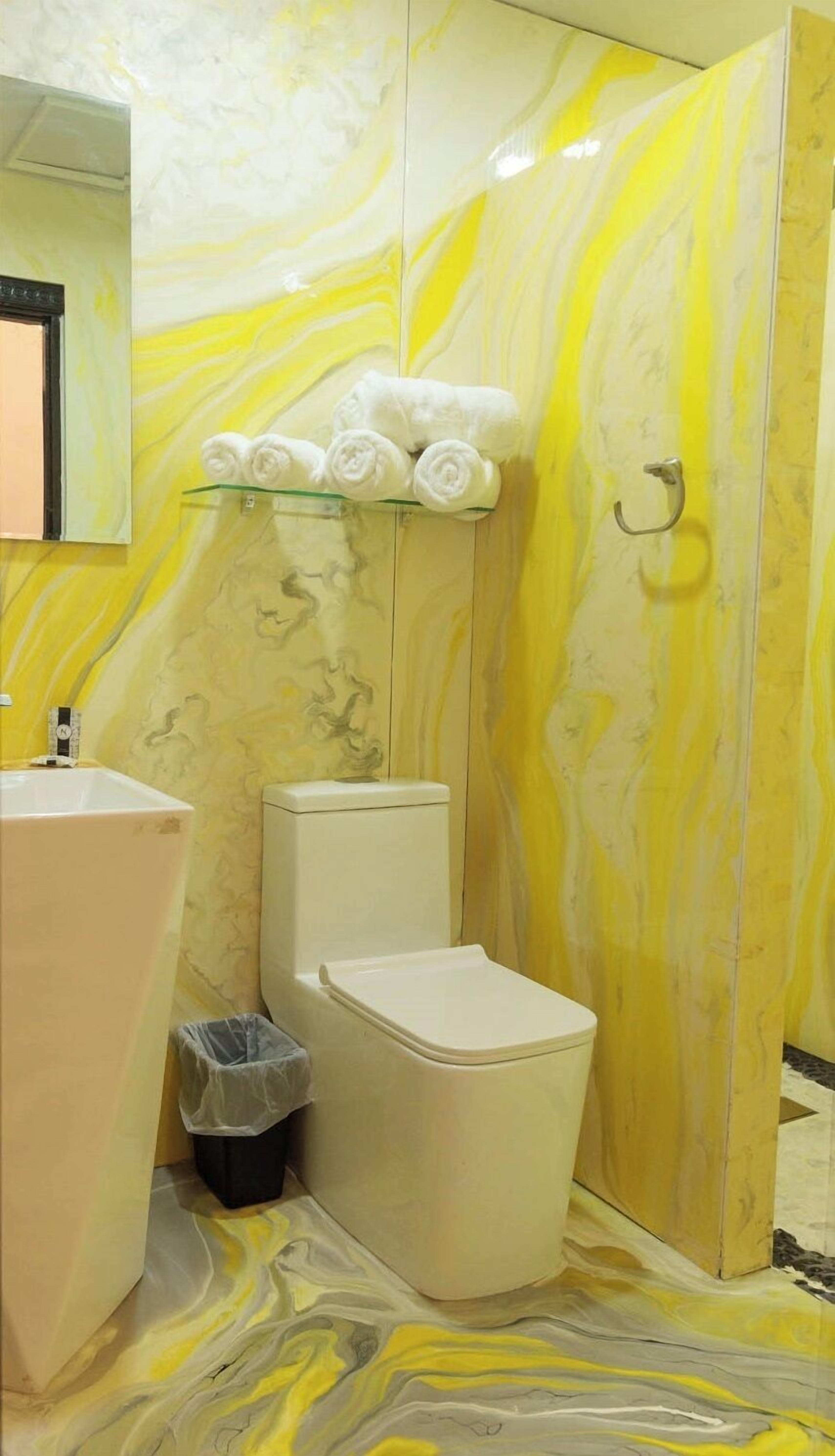 Ein Badezimmer mit Marmorwand, Toilette, Waschbecken und Handtuchhalter mit Handtüchern.