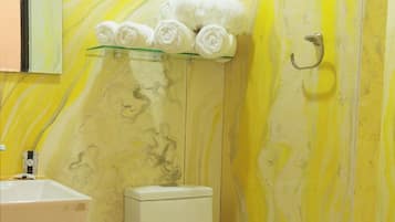 Ein Badezimmer mit Marmorwand, Toilette, Waschbecken und Handtuchhalter mit Handtüchern.