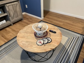 Cozy living space features a round coffee table with a woven basket and nautical-themed coasters.