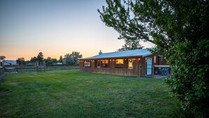 Une cabane en bois avec une cour clôturée, une véranda et une petite terrasse.