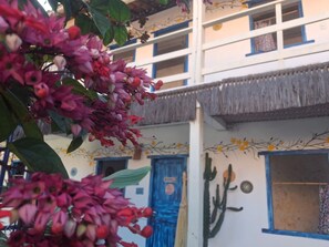 A building with a blue door, a cactus mural, and a thatched roof. - Pousada Samurai (Porto Seguro)