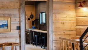 A log cabin interior with a kitchen area, wooden dining table, and a staircase. - The Log House, Montana. Handmade & luxurious cabin. 10 min from Main St.  (Lewistown)