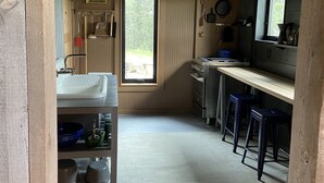 A compact kitchen with a window, wooden cabinets, and a sink. - The Log House, Montana. Handmade & luxurious cabin. 10 min from Main St. (Lewistown)