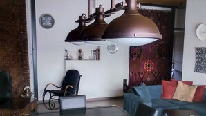 Ein modernes Wohnzimmer mit einer großen Deckenleuchte, einem Sofa, einem Couchtisch und einer Wand mit Muster.