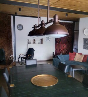 A modern living room with a large ceiling light fixture, a sofa, a coffee table, and a patterned wall.