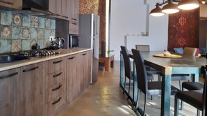 Eine moderne Küche mit Holzausstattung, einem Gasherd und einem Kühlschrank. Es gibt eine Essecke mit Tisch und Stühlen.