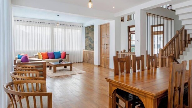 A spacious living room with wooden furniture, a dining area, and a staircase.