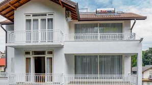 A two-story building with balconies, a garage, and a sign indicating "GREEN ROYAL VILLA".