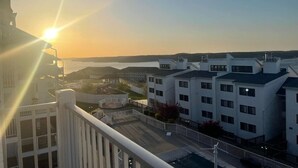 A residential building with a balcony overlooking a coastal area during sunset. - Breathtaking Lake & Pool Views, In Osage Beach! (Osage Beach)