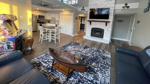A spacious living room with a fireplace, a dining area, and a kitchen in the background. - Breathtaking Lake & Pool Views, In Osage Beach! (Osage Beach)