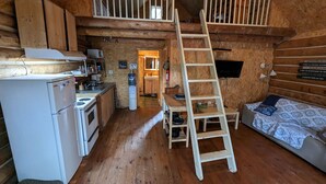 A compact cabin-style room with a kitchenette, a loft bed, and a ladder to the upper bunk. - 4 - Prunier : Chaleureux chalet en bois rond  au bord de la belle Rivière Rouge (Rivière-Rouge)