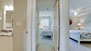 Quarto de hotel com cama, mesa de cabeceira, abajur e ventilador de teto.