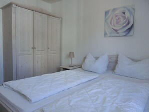 Une chambre à coucher avec un lit, une table de chevet, une lampe et une armoire.