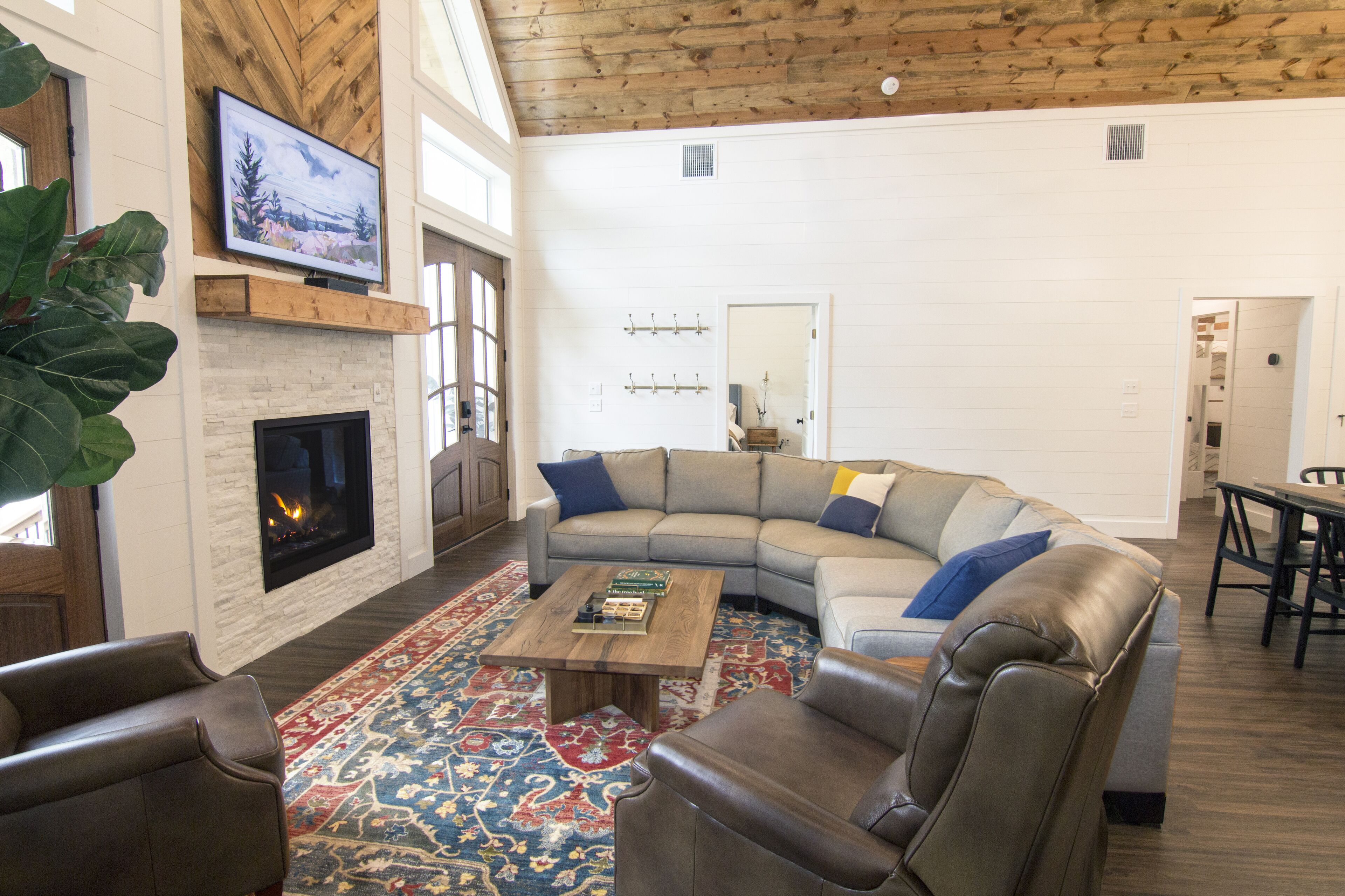 A spacious living room with a fireplace, a large sectional sofa, a coffee table, and a television mounted on the wall.