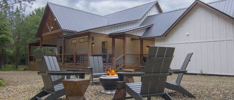 A lodge with a covered deck, outdoor seating, and a fire pit.