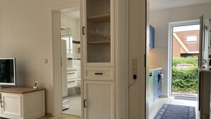 A modern kitchen with white cabinetry, a built-in oven, and a view of the backyard. - Jacobihof - Muschelsucher - Strandnahe 3-zimmer-wohnung in Ruhiger Sackgassenlage für 3 Personen (Dahme)