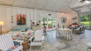A spacious room with a bed, a dining table, and a sofa. There is a large window and a ceiling fan. - Coffeyville Countryside Studio w/ Fire Pit! (Coffeyville)