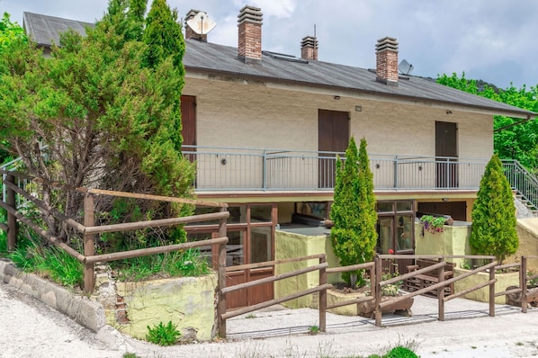 A two-story building with a balcony, a wooden fence, and a gravel driveway.