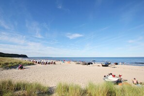 Une plage avec des bateaux, des tentes et des gens.