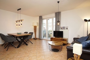 A modern living room with a dining area, a TV, and a fireplace.