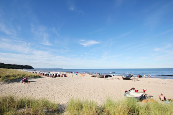 A beach with boats, tents, and people.