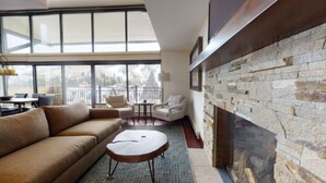 Un salon moderne avec une cheminée en pierre, de grandes fenêtres et un balcon.
