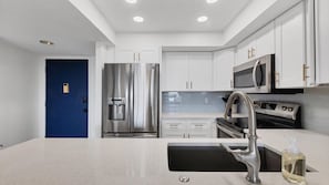 A modern kitchen with stainless steel appliances, white cabinetry, and a blue accent wall. - Anchorage Resort Siesta Key 2 Bedroom 6th Floor Condo Beach Access (Siesta Key)