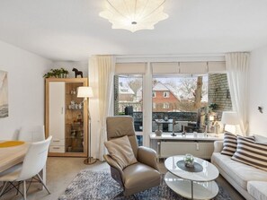 Moderni olohuone, jossa on sohva, nojatuoli, sohvapöytä ja ruokailutila.