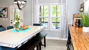 A dining area with a long table, benches, a hanging light fixture, and large windows with curtains. - Riverbend Ranch*Smith Lake Family Fun!*Dog Yard! (Crane Hill)