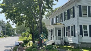 A two-story house with a porch, a tree in front, and a street sign indicating 'SENIOR'. - Cozy 1890 Cottage Studio with Hot Tub and Fire Pit in Downtown Kennebunk (Kennebunk)
