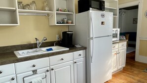 A kitchen with white cabinets, a sink, a microwave, and a refrigerator. - Cozy 1890 Cottage Studio with Hot Tub and Fire Pit in Downtown Kennebunk (Kennebunk)