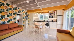 A modern kitchen with a dining area, a sofa, and a washing machine.